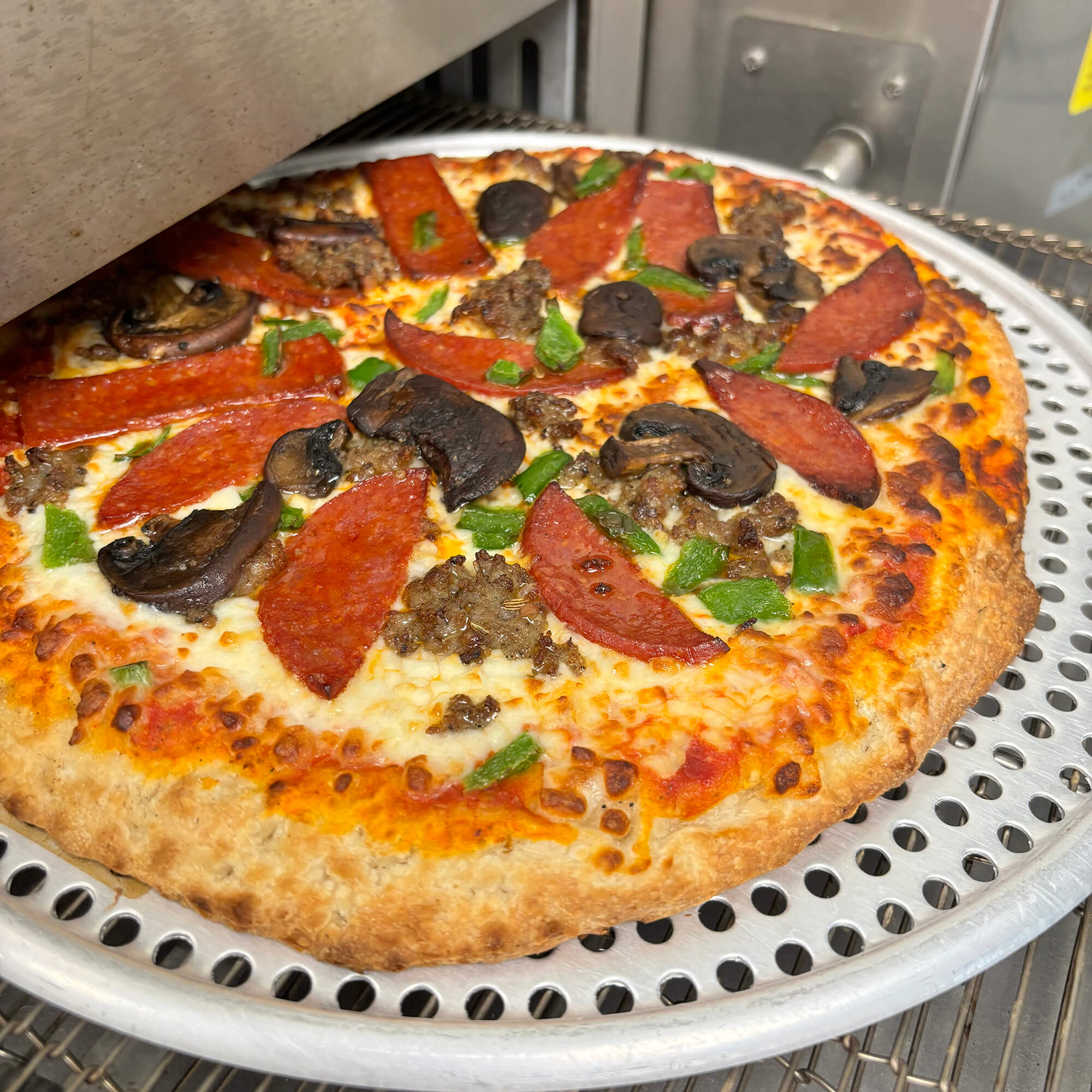 Photograph of a pizza coming out of the oven at the Brewer's Lounge