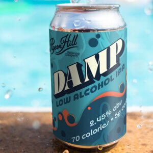 Photograph of a can of DAMP IPA near a pool.